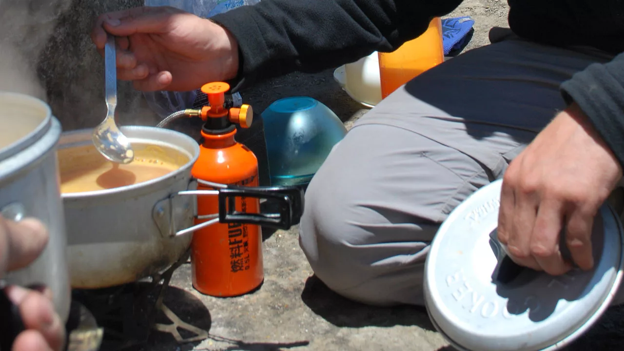 On a training program, a student cooks lunch on an MSR stove.