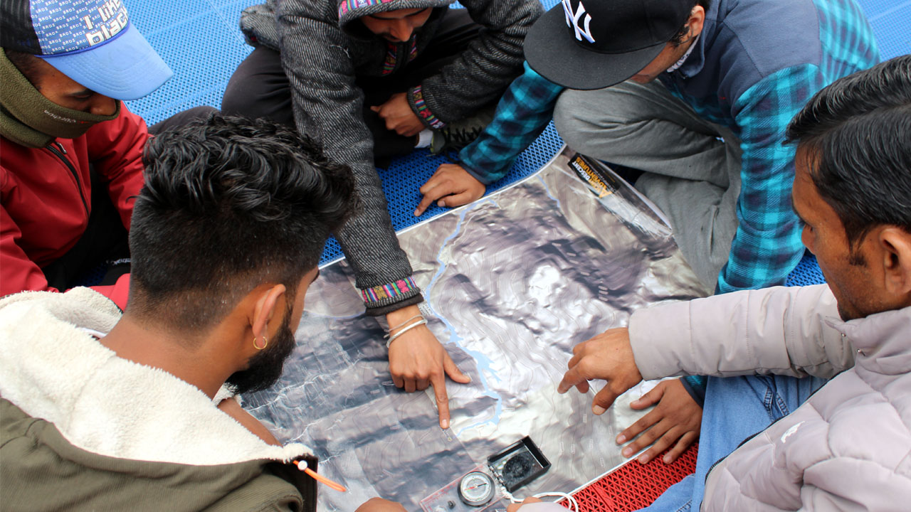 A group of students plots a route on a map using a compass in map reading skill class