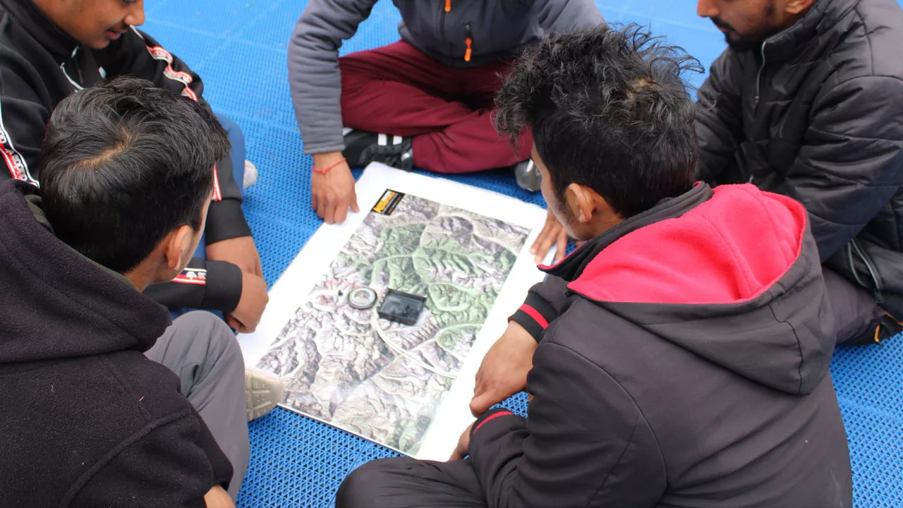 Students seated in a circle reading a map with a compass in the center