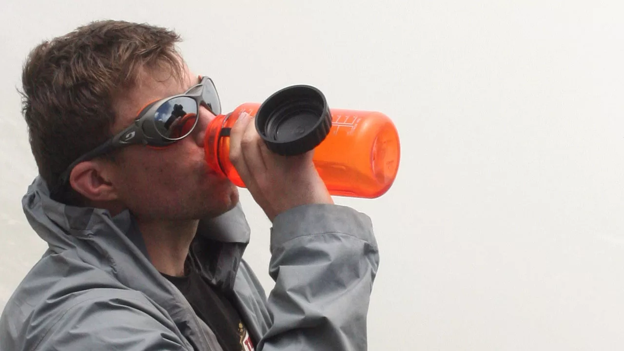 client Taking a drink from a orange water bottle with his sun shades on