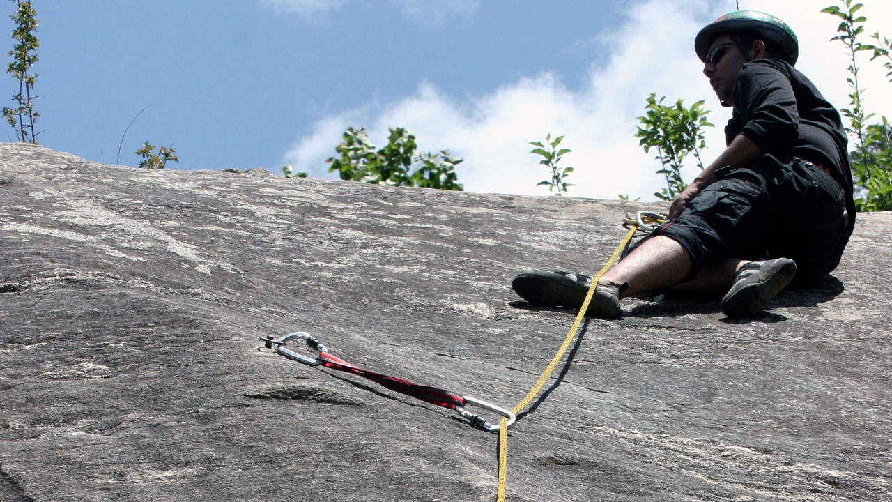 Climber resting at the end of a trad climbing pitch