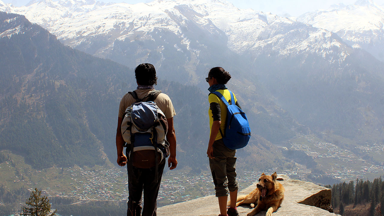 Shashi and Surrender are standing on a rock slab, next to a dog on lamadugh trek