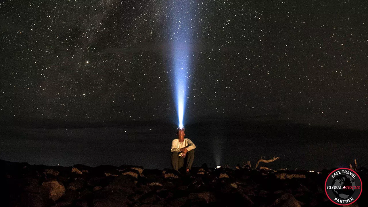 A man with a headlamp observes the Milky Way 